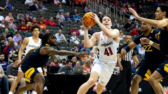 Cincinnati Bearcats guard Simas Lukosius (41) drives to the basket between West Virginia Mountaineers defenders in the first half of the Big 12 Conference tournament between Cincinnati Bearcats and West Virginia Mountaineers at T-Mobile Center in Kansas City, Mo., on Tuesday, March 12, 2024.